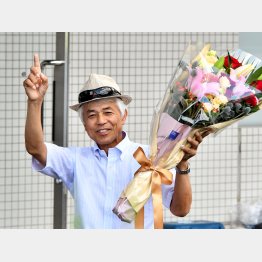 記念の花束を手に笑顔の国枝師
